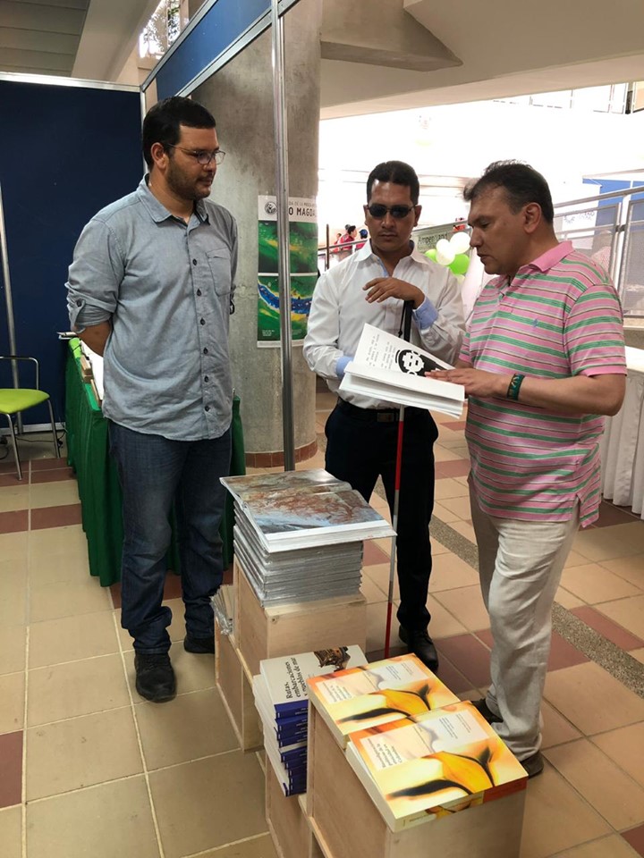 Carlos Parra Dussán, director del Instituto Nacional para Ciegos (INCI), lee el libro «De piedras y estatuas», impreso en braille por la Imprenta Nacional para Ciegos, durante su visita al estand del ICANH en la Filsmar 2019.